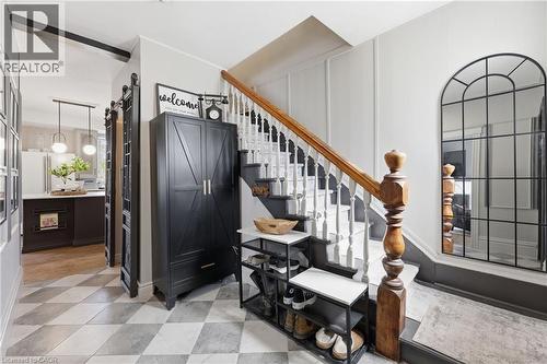 Staircase with wood balustrade and white risers, framed by a full-length arched mirror - 361 Cumberland Avenue, Hamilton, ON - Indoor Photo Showing Other Room