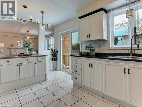 Kitchen featuring white cabinetry with dark hardware, dark countertops, and a double basin sink with a pull-down faucet - 154 Deerpath Drive, Guelph, ON - Indoor Photo Showing Kitchen With Double Sink