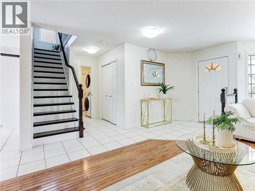 Bright entryway with tile flooring, featuring a staircase with dark treads and a wood-finish handrail - 154 Deerpath Drive, Guelph, ON - Indoor Photo Showing Other Room