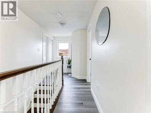 Upper-level hallway featuring wood-finish flooring, a white spindle staircase with a dark wood handrail, and a window providing natural light - 154 Deerpath Drive, Guelph, ON - Indoor Photo Showing Other Room