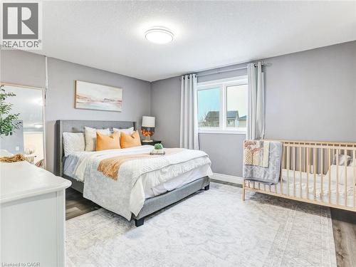 Bedroom featuring wood-finish flooring, a contemporary ceiling light fixture, and a window with curtains - 154 Deerpath Drive, Guelph, ON - Indoor Photo Showing Bedroom