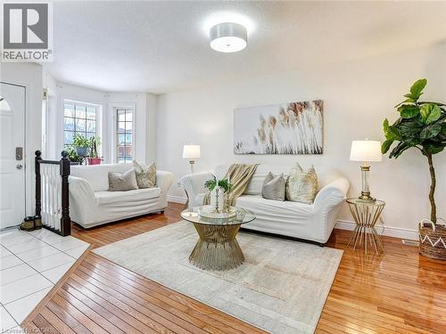 Bright living area featuring wood-finish flooring, white walls, a bay window with multiple panes, a white ceiling, and a flush mount light fixture - 154 Deerpath Drive, Guelph, ON - Indoor Photo Showing Living Room
