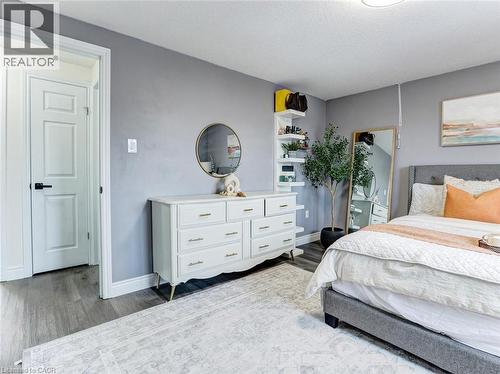 Spacious interior room featuring wood-finish flooring, light gray walls, a white paneled door with black hardware, and a ceiling light fixture - 154 Deerpath Drive, Guelph, ON - Indoor Photo Showing Bedroom