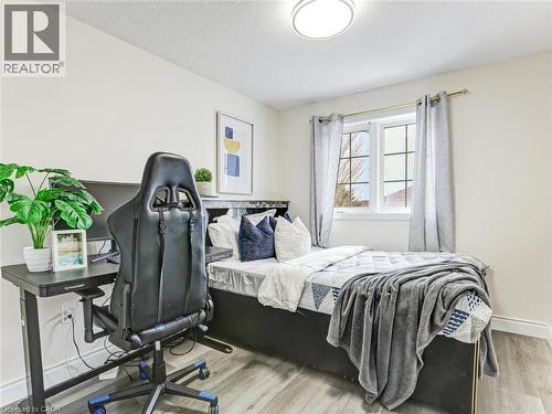 Bright bedroom featuring light-toned walls, wood-finish flooring, a window with natural light, and a flush-mount ceiling light fixture - 154 Deerpath Drive, Guelph, ON - Indoor Photo Showing Bedroom