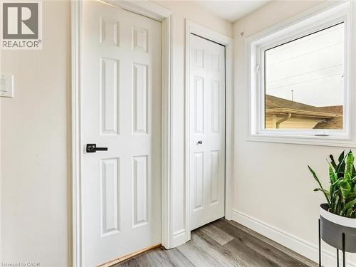 Room featuring wood-finish flooring, a white six-panel door with black hardware, and a white bi-fold door - 154 Deerpath Drive, Guelph, ON - Indoor Photo Showing Other Room