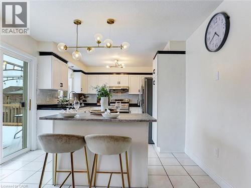 Modern kitchen featuring white cabinetry with black trim, a central island with bar seating, and a sliding glass door - 154 Deerpath Drive, Guelph, ON - Indoor Photo Showing Kitchen With Upgraded Kitchen