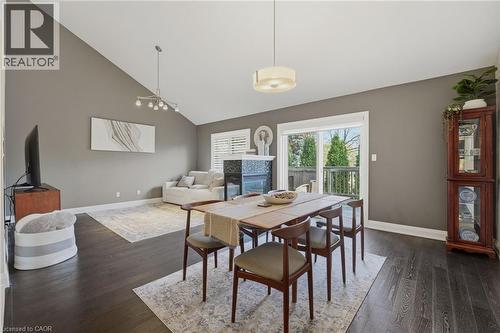 Spacious open-concept living area featuring dark wood-finish flooring, vaulted ceilings, and a modern fireplace with a white mantel and black surround - 7 Gibson Place Unit# 26, St. Catharines, ON - Indoor