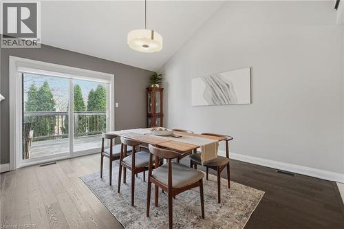 Dining area featuring a vaulted ceiling, wood-finish flooring, and a sliding glass door opening to an exterior deck - 7 Gibson Place Unit# 26, St. Catharines, ON - Indoor Photo Showing Dining Room