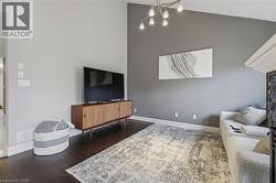 Living area featuring soaring ceiling height, dark wood-finish flooring, and a contemporary multi-light fixture - 