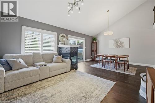 Vaulted ceiling living space featuring dark wood-finish flooring, a contemporary chandelier, and a fireplace with a dark tile surround - 7 Gibson Place Unit# 26, St. Catharines, ON - Indoor Photo Showing Living Room