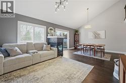 Vaulted ceiling living space featuring dark wood-finish flooring, a contemporary chandelier, and a fireplace with a dark tile surround - 