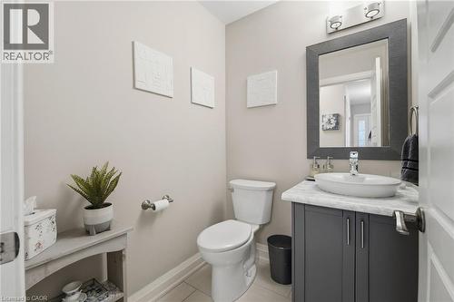 Modern powder room featuring a gray vanity with a vessel sink, a white countertop, and contemporary wall sconces - 7 Gibson Place Unit# 26, St. Catharines, ON - Indoor Photo Showing Bathroom