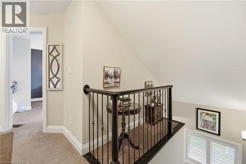 Carpeted hallway featuring a wrought iron railing, white trim, and a window with plantation shutters - 7 Gibson Place Unit# 26, St. Catharines, ON - Indoor Photo Showing Other Room