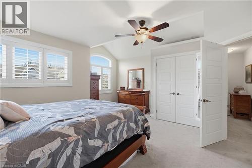 Vaulted ceiling bedroom featuring white plantation shutters, an arched window, a ceiling fan with integrated lighting, and two sets of white paneled doors - 7 Gibson Place Unit# 26, St. Catharines, ON - Indoor Photo Showing Bedroom