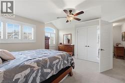 Vaulted ceiling bedroom featuring white plantation shutters, an arched window, a ceiling fan with integrated lighting, and two sets of white paneled doors - 