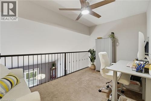 Carpeted loft space featuring a black iron railing, a contemporary ceiling fan with integrated lighting, and a sloped ceiling - 7 Gibson Place Unit# 26, St. Catharines, ON - Indoor Photo Showing Office