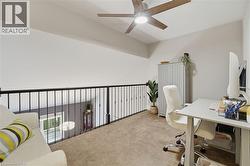 Carpeted loft space featuring a black iron railing, a contemporary ceiling fan with integrated lighting, and a sloped ceiling - 