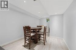 Lower-level living space featuring recessed lighting, light wood-finish flooring, white baseboards, and a window providing natural light - 