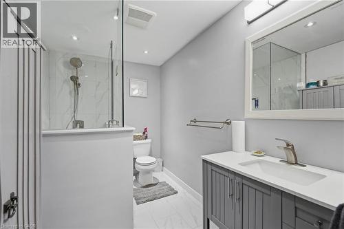Contemporary bathroom featuring a glass-enclosed shower with white marble-look tile, a grey vanity with a white countertop and integrated sink, a large framed mirror, and recessed ceiling lighting - 7 Gibson Place Unit# 26, St. Catharines, ON - Indoor Photo Showing Bathroom