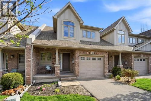 Brick facade townhome with an integrated garage, covered front porch, and dormer windows - 7 Gibson Place Unit# 26, St. Catharines, ON - Outdoor With Deck Patio Veranda With Facade