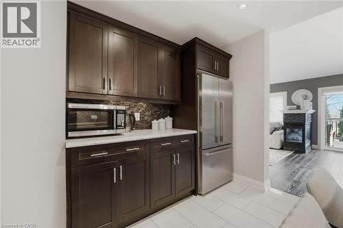 Kitchenette featuring dark wood-finish cabinetry, stainless steel refrigerator, and built-in microwave - 7 Gibson Place Unit# 26, St. Catharines, ON - Indoor Photo Showing Kitchen