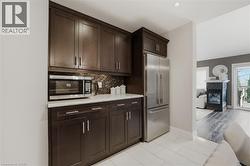 Kitchenette featuring dark wood-finish cabinetry, stainless steel refrigerator, and built-in microwave - 