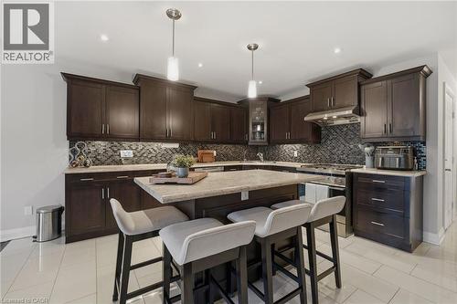 Kitchen featuring dark wood-finish cabinetry, light-toned countertops, and a patterned backsplash - 7 Gibson Place Unit# 26, St. Catharines, ON - Indoor