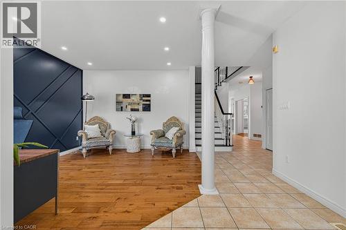 Interior space featuring a decorative accent wall, recessed lighting, wood-finish flooring, and a staircase with dark banisters - 14 Hearthbridge Street, Kitchener, ON - Indoor Photo Showing Other Room