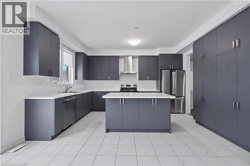 Modern kitchen featuring extensive gray cabinetry, white countertops, stainless steel appliances, a central island, and white tile flooring - 123 Rea Drive, Fergus, ON - Indoor Photo Showing Kitchen With Upgraded Kitchen