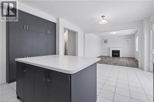 Kitchen featuring a center island with a light-toned countertop, dark gray cabinetry, and white tile flooring - 123 Rea Drive, Fergus, ON - Indoor