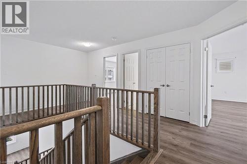 Staircase with wood-finish handrails and balusters, featuring wood-finish flooring, white walls, and white interior doors - 123 Rea Drive, Fergus, ON - Indoor Photo Showing Other Room