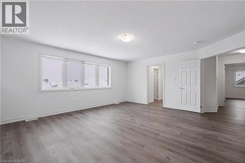 Spacious room featuring wide plank wood-finish flooring, white baseboards, and a neutral wall palette - 123 Rea Drive, Fergus, ON - Indoor Photo Showing Other Room