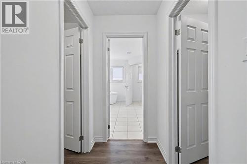 White painted interior hallway featuring dark wood-finish flooring, white trim, and panel doors - 123 Rea Drive, Fergus, ON - Indoor Photo Showing Other Room