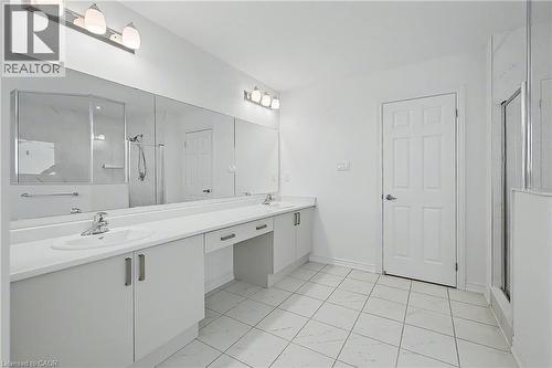 Spacious bathroom featuring a dual vanity with built-in sinks, ample counter space, custom cabinetry, tiled flooring, and a glass-enclosed shower - 123 Rea Drive, Fergus, ON - Indoor Photo Showing Bathroom