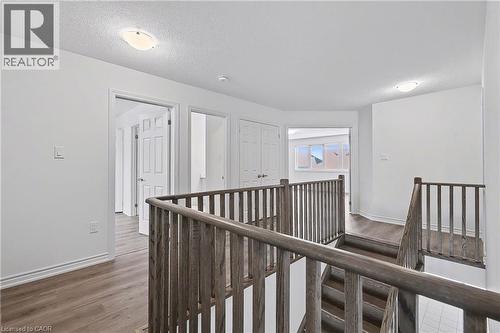 Upper-level hallway featuring wood-finish flooring, white walls, and multiple doorways - 123 Rea Drive, Fergus, ON - Indoor Photo Showing Other Room