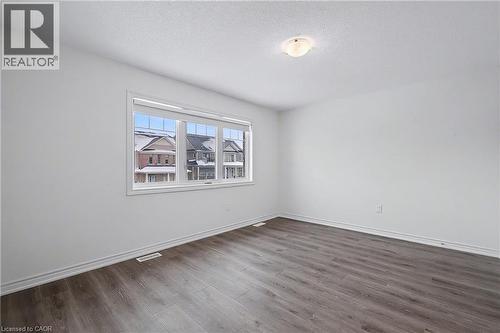 Bright room featuring wood-finish flooring, white baseboards, and a large window with white trim - 123 Rea Drive, Fergus, ON - Indoor Photo Showing Other Room