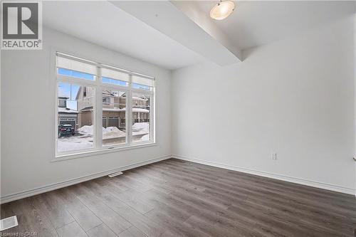 Spacious interior featuring a large multi-pane window, wood-finish flooring, white walls, and a semi-flush mount ceiling light - 123 Rea Drive, Fergus, ON - Indoor Photo Showing Other Room