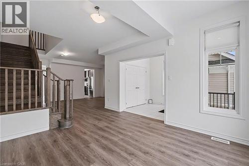 Spacious interior featuring wood-finish flooring, a contemporary staircase with wood railings, recessed lighting, and a brightly lit entryway with white tile - 123 Rea Drive, Fergus, ON - Indoor Photo Showing Other Room