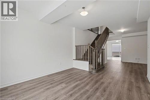 Open-concept interior featuring wood-finish flooring, a traditional wooden staircase with balusters, and a recessed ceiling element - 123 Rea Drive, Fergus, ON - Indoor Photo Showing Other Room