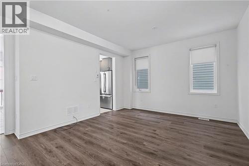 Open-concept living space featuring wood-finish flooring, white walls, and two windows with blinds - 123 Rea Drive, Fergus, ON - Indoor Photo Showing Other Room