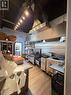 Commercial kitchen featuring extensive stainless steel surfaces, a large industrial exhaust hood system, track lighting, and wood-finish flooring - 4322 Ontario Street Unit# 1, Lincoln, ON 