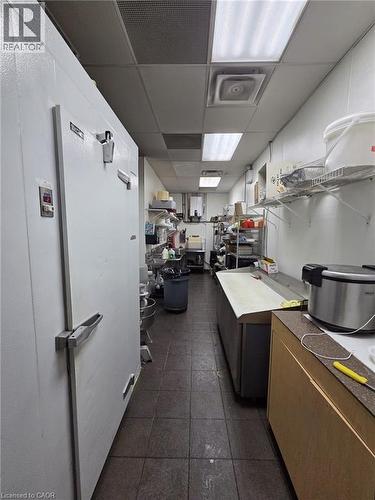 Commercial kitchen space featuring a large walk-in cooler, tiled flooring, drop ceiling with fluorescent lighting, and extensive counter space - 4322 Ontario Street Unit# 1, Lincoln, ON 