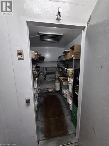Walk-in cold storage unit featuring a metal door, interior wall-mounted temperature display, ceiling-mounted refrigeration unit, and integrated wire shelving throughout - 4322 Ontario Street Unit# 1, Lincoln, ON 