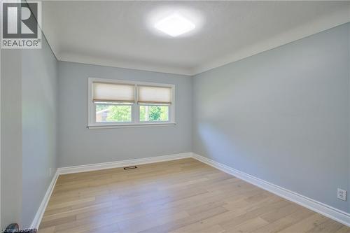 Bright interior room featuring wood-finish flooring, light blue walls, and white crown molding - 31 Brodick Street, Hamilton, ON - Indoor Photo Showing Other Room