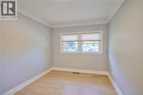 Light-filled room featuring a double window with blinds, light wood-finish flooring, and crown molding - 31 Brodick Street, Hamilton, ON - Indoor Photo Showing Other Room