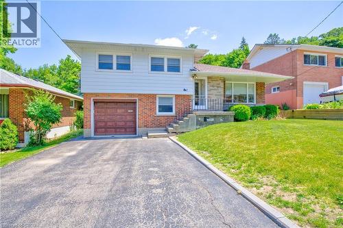 Split-level residence featuring a brick and white siding exterior, an integrated single-car garage, a paved driveway, and a front porch with stone accents - 31 Brodick Street, Hamilton, ON - Outdoor