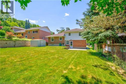 Spacious backyard featuring a lush lawn, a retaining wall, a storage shed, and a concrete patio - 31 Brodick Street, Hamilton, ON - Outdoor With Backyard With Exterior