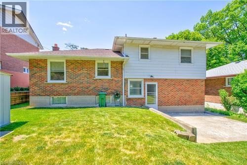 Rear exterior featuring brick and siding construction, multiple windows, a ground-level access door, and a concrete driveway - 31 Brodick Street, Hamilton, ON - Outdoor With Exterior