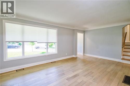 Spacious interior room featuring light wood-finish flooring, a large multi-pane window with white roller shades, and light-toned wall finishes - 31 Brodick Street, Hamilton, ON - Indoor Photo Showing Other Room