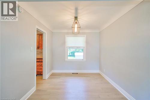 Bright interior space featuring light wood-finish flooring, a contemporary geometric pendant light fixture, and crown molding - 31 Brodick Street, Hamilton, ON - Indoor Photo Showing Other Room